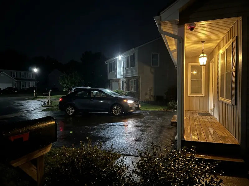 House driveway at night with a small security camera under the porch